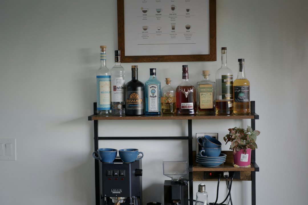 A home coffee station with a Gaggia espresso machine and liquor bottles on shelves