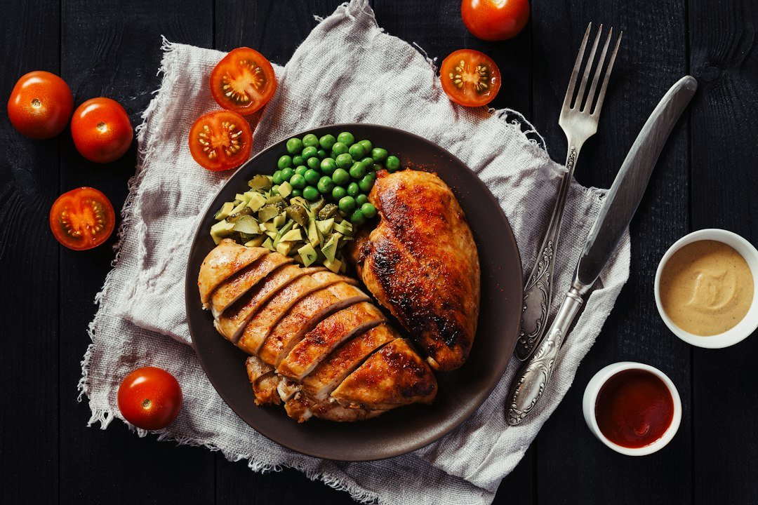 Cooked chicken with vegetables and sauces on a dinner plate; illustrative meal context.